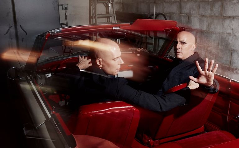 A Perfect Circle band members posing inside a vintage red convertible car, photo by Travis Shinn.